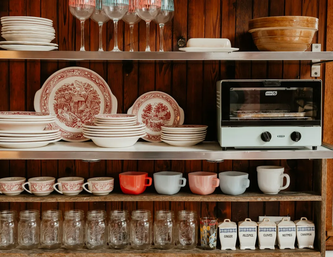 Kitchen shelves holding dishes, mugs and glasses