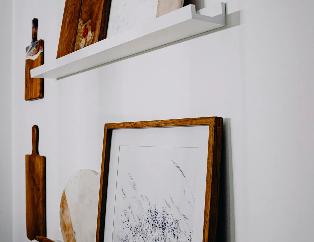 Wall-mounted timber shelves displaying artwork and cutting boards